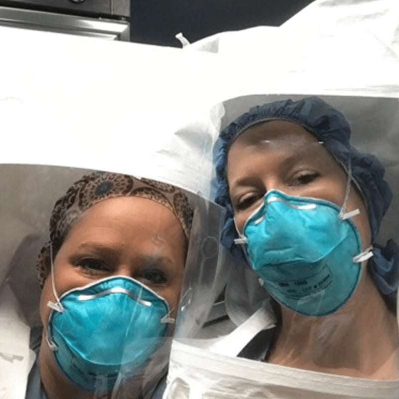 Two individuals in surgical attire with face masks in a medical setting.