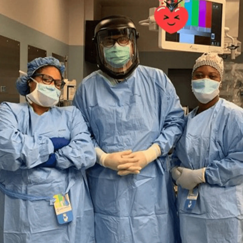 Three medical professionals in protective gear posing for a photo in a hospital setting.