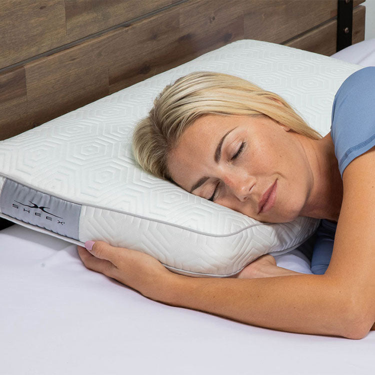 Woman laying on INFINITE ZEN Pillow looking happy with eyes closed.