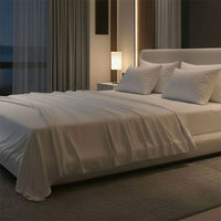 Modern bedroom with a large bed, nightstands, and a lamp near a window with curtains. Bed has Nightfall Sheet Sets in Cloud White color.#choose-your-color_cloud-white