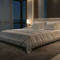 Modern bedroom with a large bed, nightstands, and a lamp near a window with curtains. Bed has Nightfall Sheet Sets in Cloud White color.#choose-your-color_cloud-white