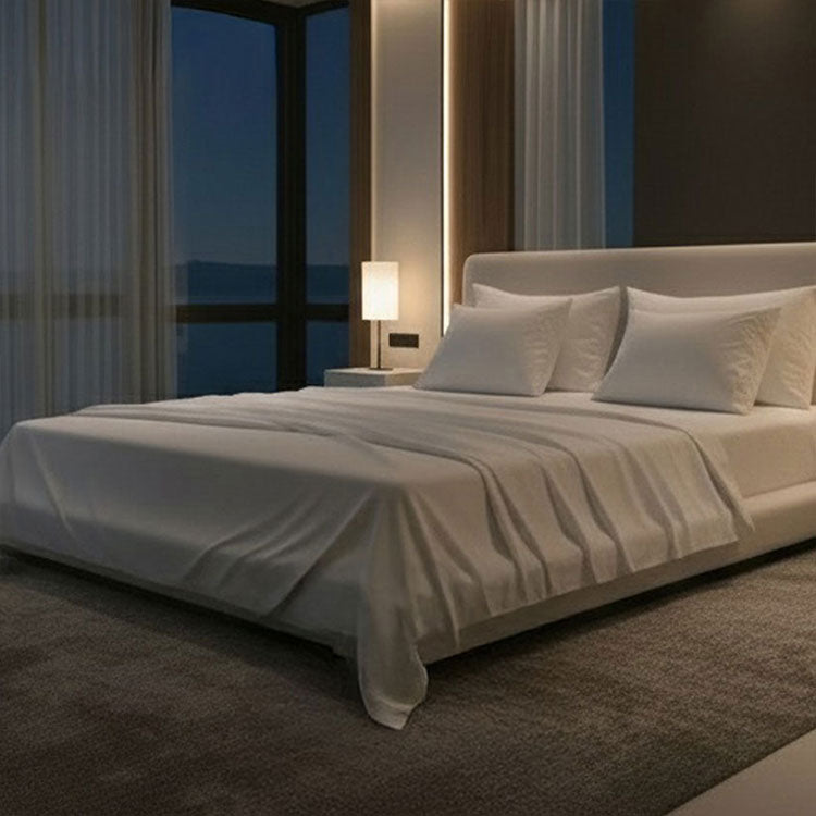 Modern bedroom with a large bed, nightstands, and a lamp near a window with curtains. Bed has Nightfall Sheet Sets in Cloud White color.#choose-your-color_cloud-white