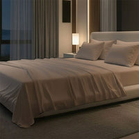 Modern bedroom with a large bed, nightstands, and a lamp near a window with curtains. Bed has Nightfall Sheet Sets in Sand Dune color.#choose-your-color_sand-dune