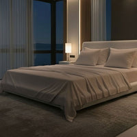 Modern bedroom with a large bed, nightstands, and a lamp near a window with curtains. Bed has Nightfall Sheet Sets in Sand Dune color.#choose-your-color_sand-dune