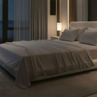 Modern bedroom with a large bed, nightstands, and a lamp near a window with curtains. Bed has Nightfall Sheet Sets in Silver Dusk color.#choose-your-color_silver-dusk
