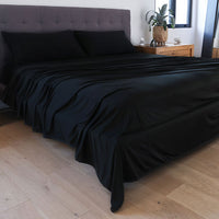 Black sheet set shown on bed in bedroom environment. #choose-your-color_black