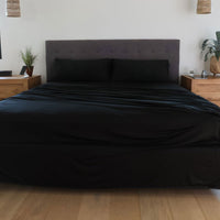 Black sheet set shown on bed in bedroom environment. #choose-your-color_black