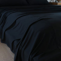 Black sheet set shown on bed in bedroom environment. #choose-your-color_black