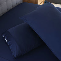 Navy Blue pillowcase set shown on bed in bedroom environment. #choose-your-color_navy