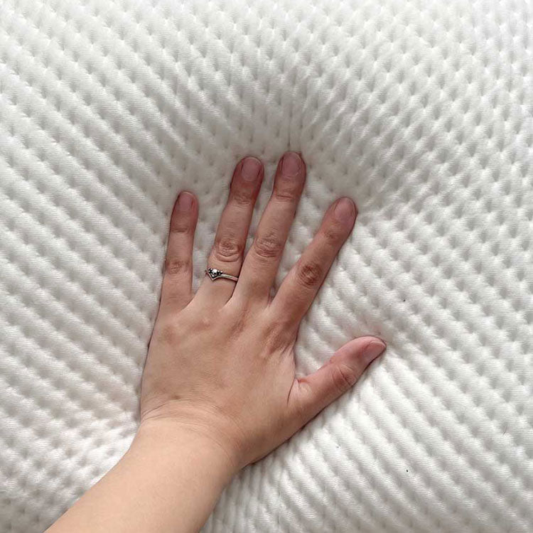 Hand pressing down on the front of the Versa Cloud pillow. Showing the soft-yet supportive nature of the pillow.