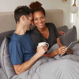 Models sitting in bed covered with Original Performance Sheets featured in Graphite.