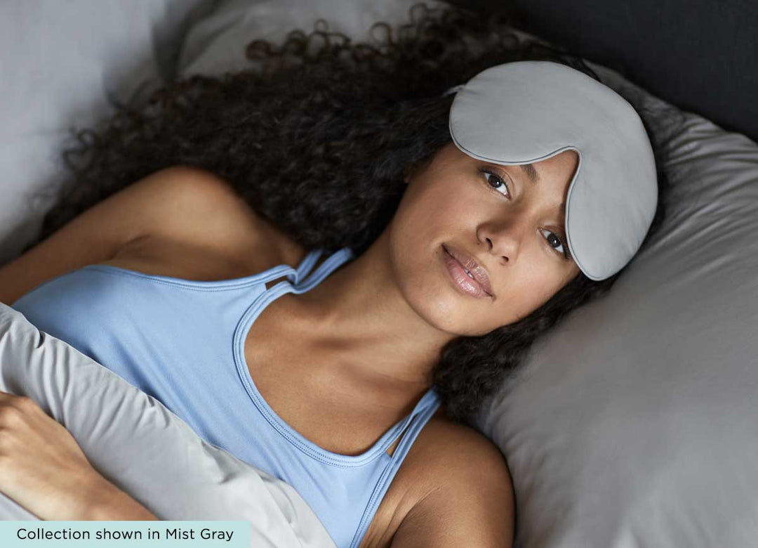 midnight label-sleep mask + travel pouch - mist gray color on model in bed #choose-your-color_porcelain