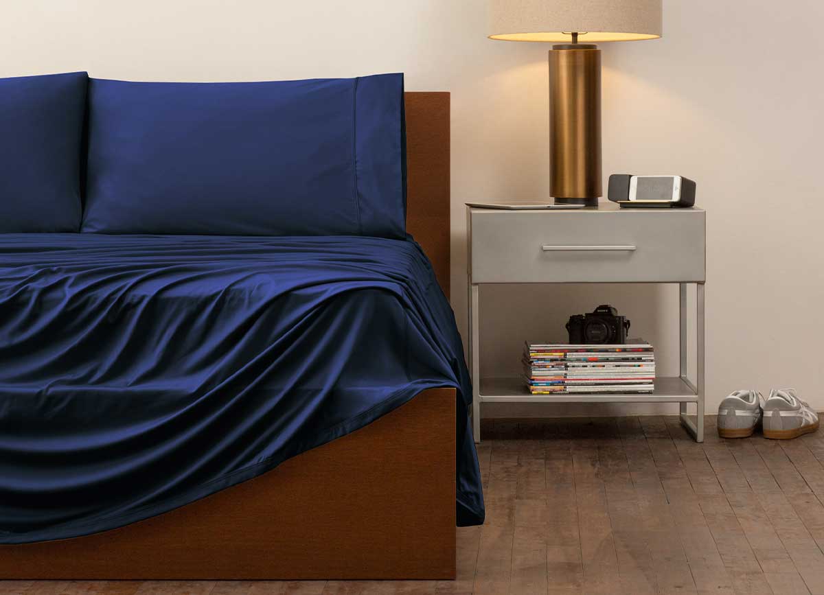 reNEWed Sheet Set on bed in room environment, Navy #choose-your-color_navy
