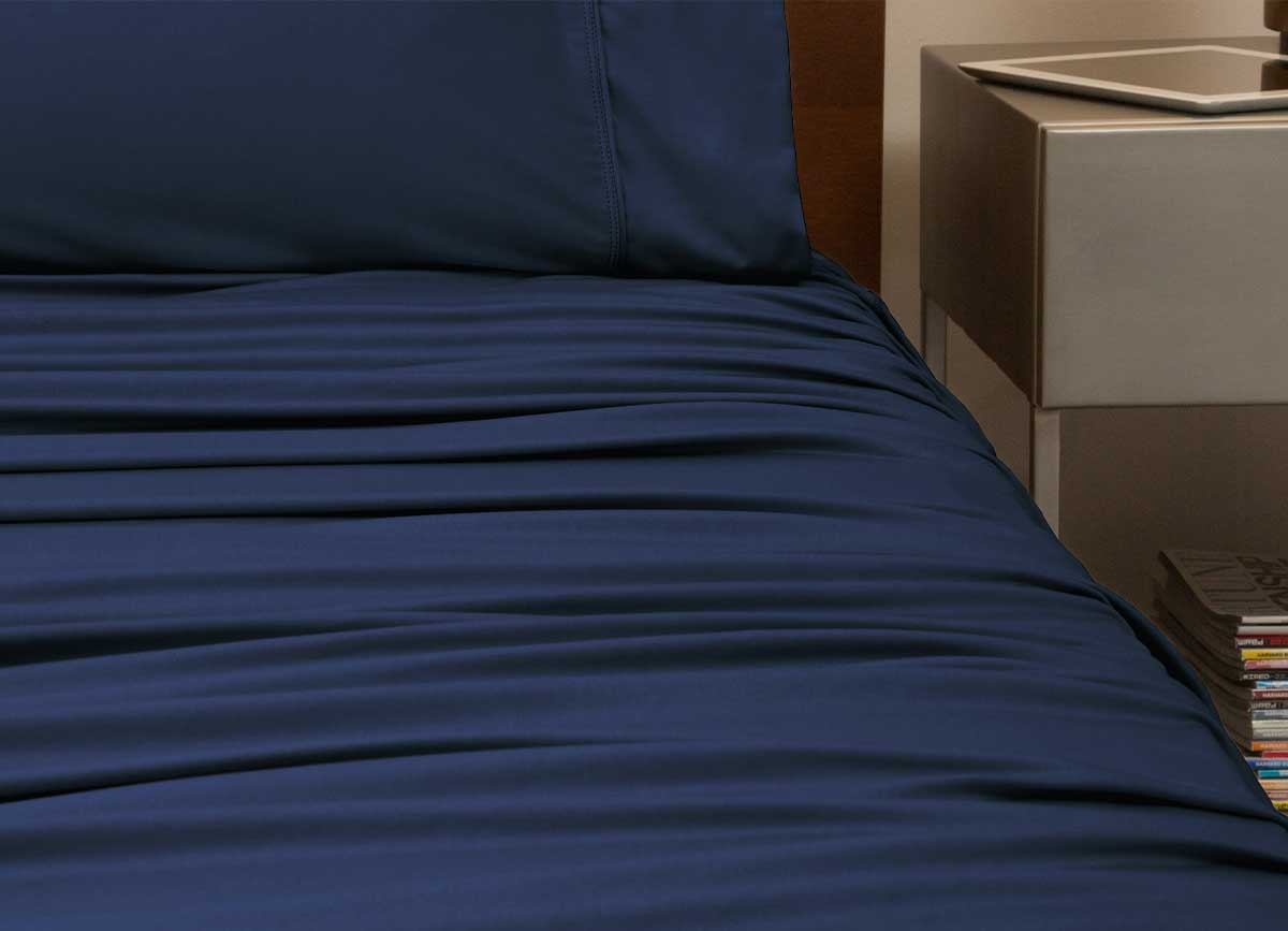 reNEWed Sheet Set on bed in room environment, Navy #choose-your-color_navy
